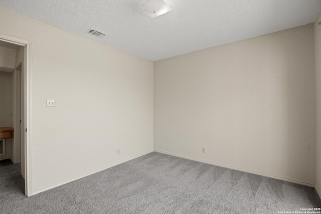 carpeted empty room featuring a textured ceiling, visible vents, and baseboards