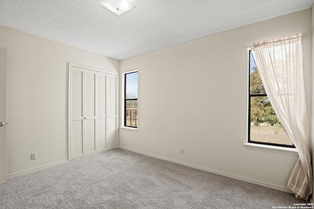 unfurnished bedroom with carpet, a closet, a textured ceiling, and baseboards