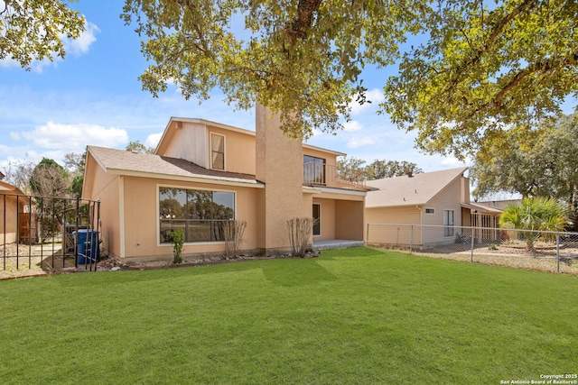 back of property with a fenced backyard, a lawn, and a balcony