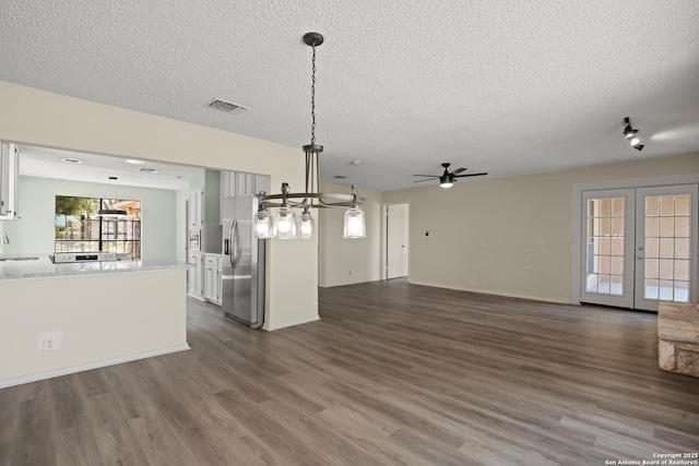 unfurnished living room with french doors, dark wood-style flooring, visible vents, a sink, and a textured ceiling