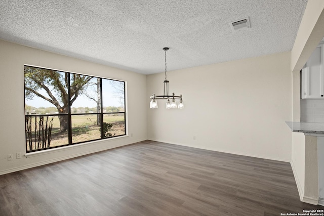 unfurnished dining area with visible vents, a notable chandelier, baseboards, and wood finished floors