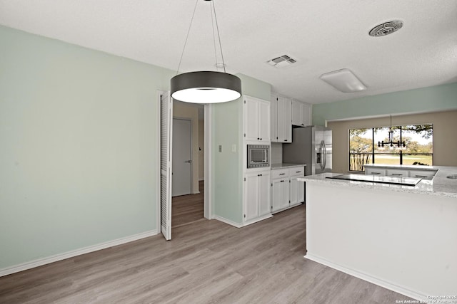 kitchen featuring stainless steel appliances, light wood-style flooring, visible vents, and white cabinets