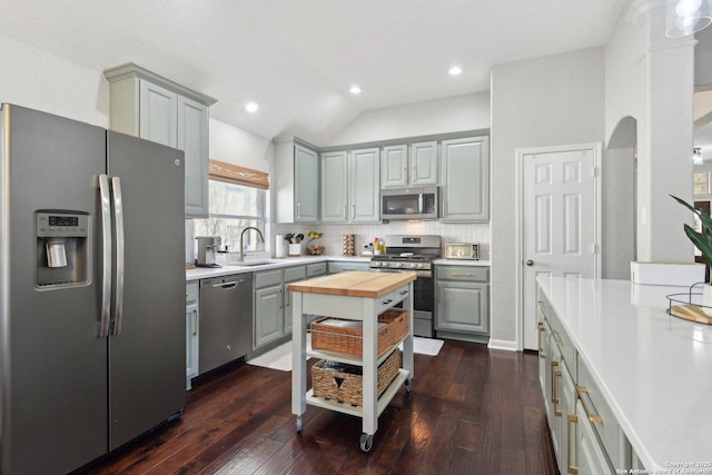 kitchen with gray cabinetry, a sink, wood counters, appliances with stainless steel finishes, and dark wood-style floors