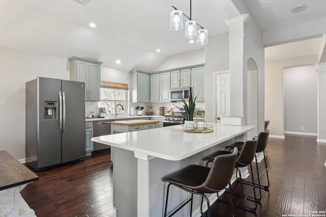 kitchen with stainless steel appliances, a peninsula, gray cabinetry, and dark wood-style floors