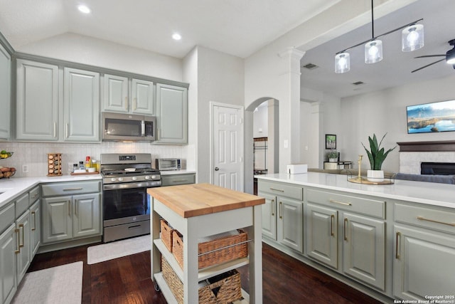 kitchen with dark wood finished floors, stainless steel appliances, tasteful backsplash, gray cabinets, and wooden counters