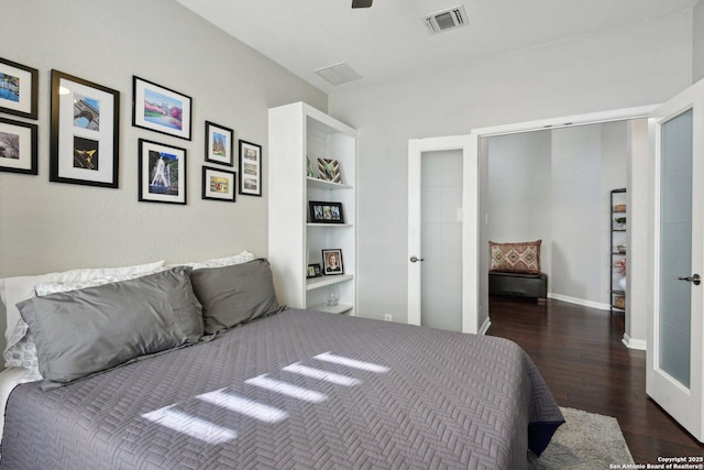 bedroom with baseboards, visible vents, and wood finished floors