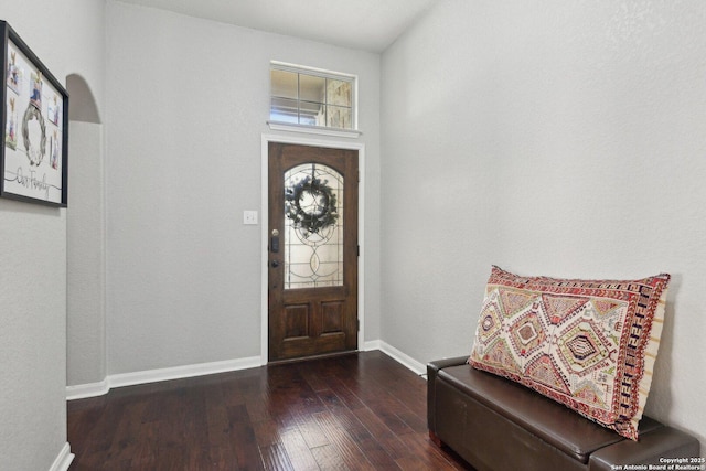 foyer featuring arched walkways, baseboards, and hardwood / wood-style flooring