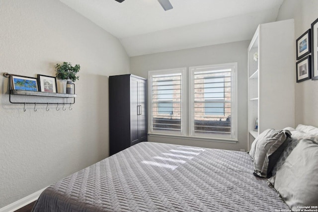 bedroom featuring a ceiling fan, lofted ceiling, and a textured wall