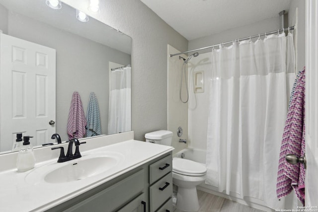 bathroom with shower / tub combo with curtain, a textured wall, toilet, vanity, and a textured ceiling