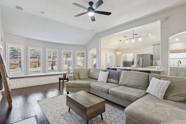 living room with ceiling fan, vaulted ceiling, and dark wood finished floors