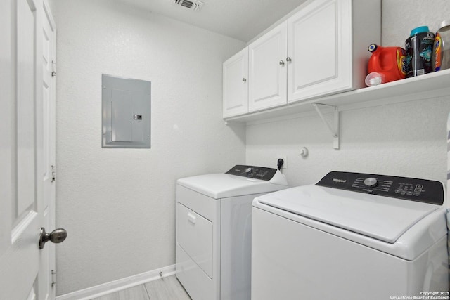 clothes washing area with cabinet space, electric panel, visible vents, baseboards, and washer and dryer