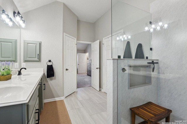 bathroom with double vanity, baseboards, walk in shower, and a sink