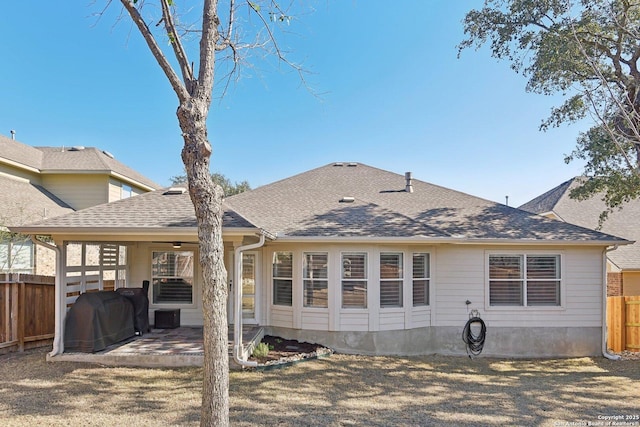 rear view of property featuring a patio area, fence, and roof with shingles