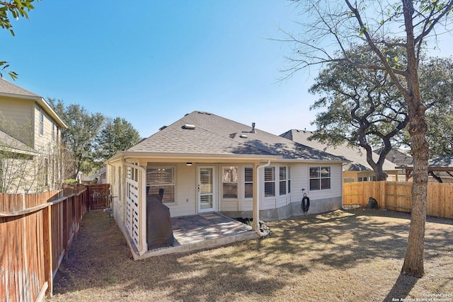 back of property featuring a patio, roof with shingles, and a fenced backyard