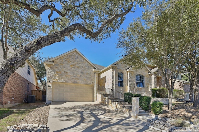 view of front of home featuring a garage, stone siding, fence, and driveway