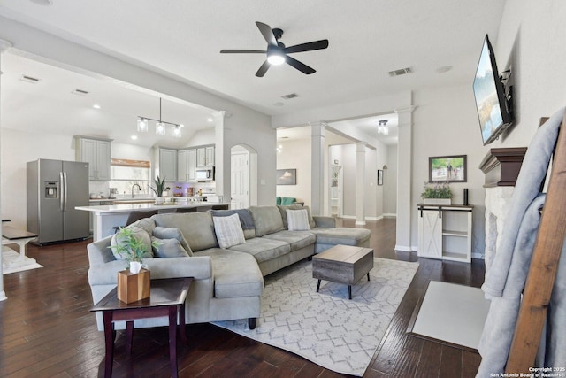 living area with dark wood-style floors, lofted ceiling, visible vents, and ornate columns