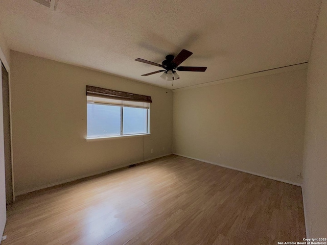 empty room with a ceiling fan, a textured ceiling, baseboards, and wood finished floors