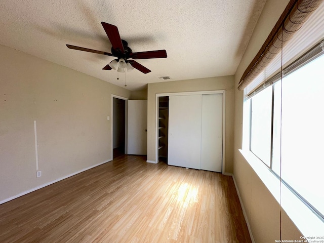 unfurnished bedroom with visible vents, ceiling fan, a textured ceiling, light wood-type flooring, and a closet