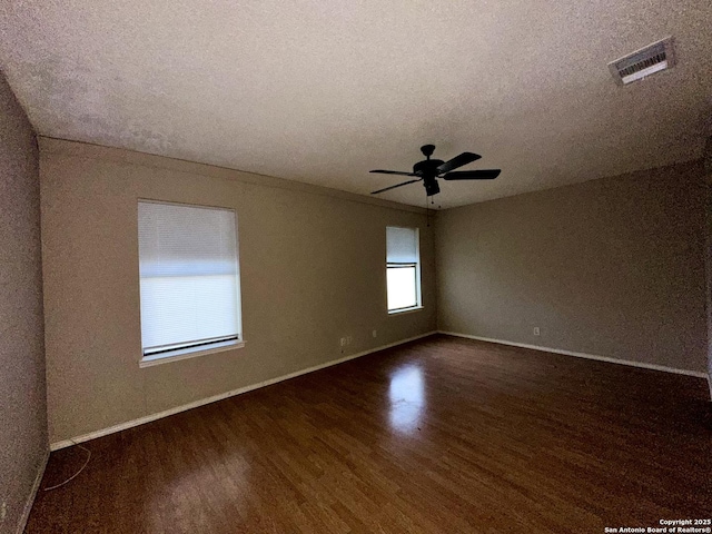 empty room with visible vents, ceiling fan, a textured ceiling, wood finished floors, and baseboards