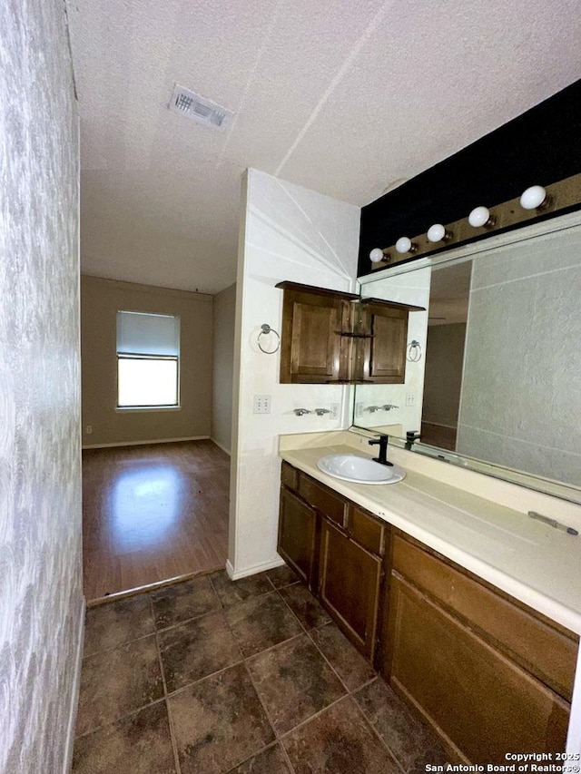 bathroom featuring a textured ceiling, vanity, visible vents, and baseboards