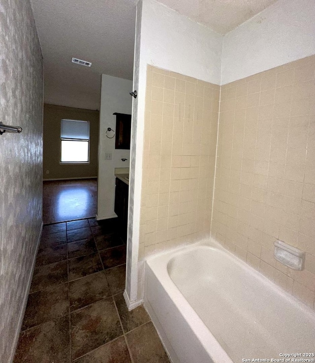 full bath featuring a textured ceiling, visible vents, and baseboards