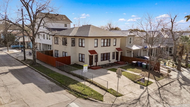 exterior space with a fenced front yard, a residential view, roof with shingles, and stucco siding