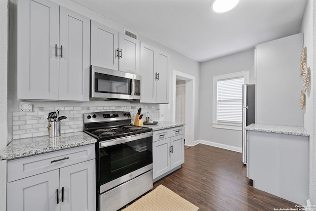 kitchen featuring backsplash, white cabinetry, appliances with stainless steel finishes, baseboards, and dark wood-style flooring