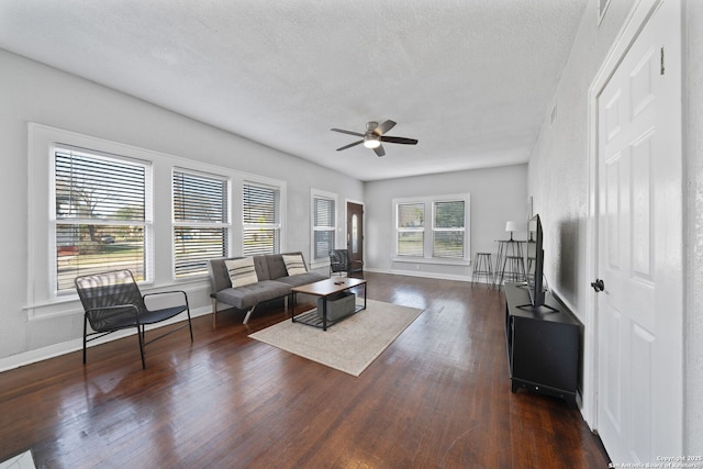 living room featuring baseboards, a textured ceiling, wood finished floors, and a ceiling fan