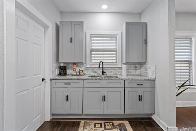 kitchen with decorative backsplash, gray cabinets, dark wood-type flooring, and a sink