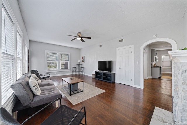 living room featuring visible vents, a ceiling fan, wood finished floors, arched walkways, and baseboards