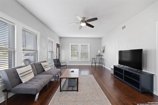 living area with baseboards, wood finished floors, visible vents, and ceiling fan