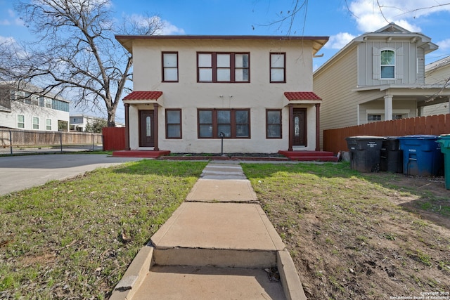 view of front of home featuring stucco siding, a tile roof, a front lawn, and fence