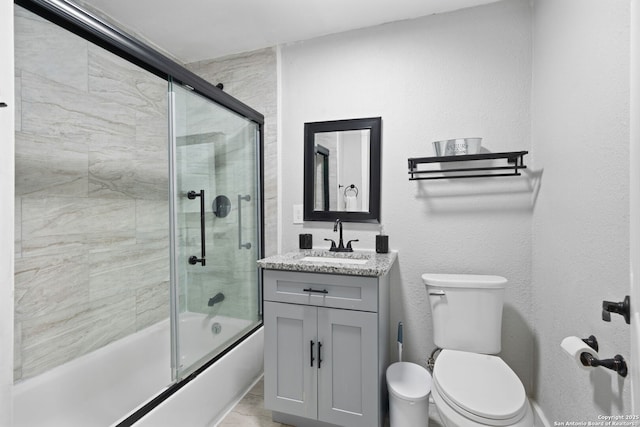 bathroom with toilet, vanity, and bath / shower combo with glass door