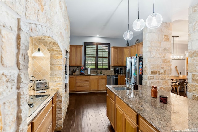 kitchen with a sink, stainless steel appliances, light stone countertops, and dark wood-style flooring