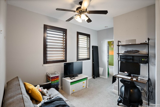 carpeted office space featuring a ceiling fan and baseboards