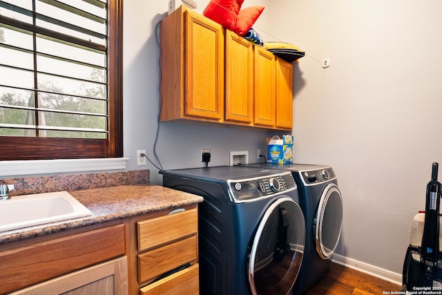 washroom featuring dark wood-type flooring, baseboards, washer and clothes dryer, cabinet space, and a sink