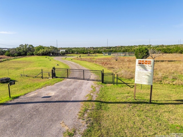 exterior space with a rural view, driveway, fence, and a gate