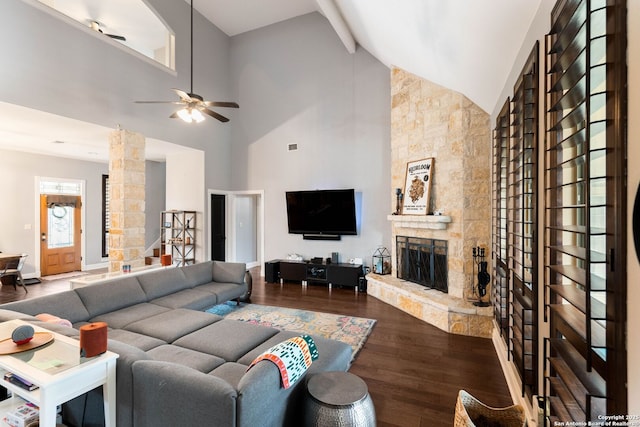 living room with high vaulted ceiling, a ceiling fan, wood finished floors, a stone fireplace, and stairs