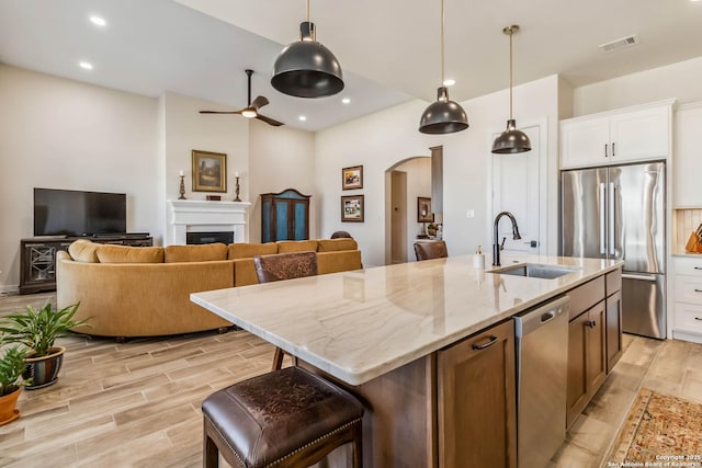 kitchen with visible vents, wood finish floors, arched walkways, a sink, and stainless steel appliances