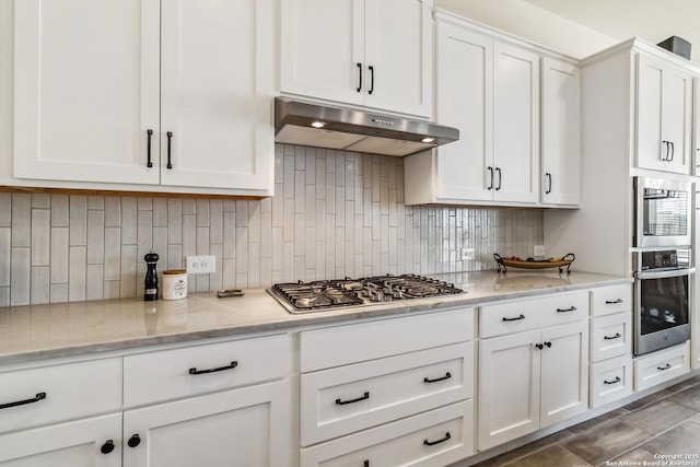 kitchen featuring white cabinets, tasteful backsplash, under cabinet range hood, and stainless steel gas cooktop