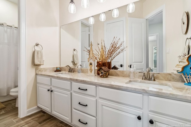 full bathroom featuring double vanity, toilet, wood finished floors, and a sink