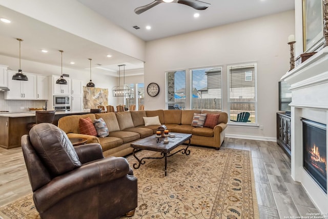 living area with a ceiling fan, visible vents, light wood finished floors, recessed lighting, and a glass covered fireplace