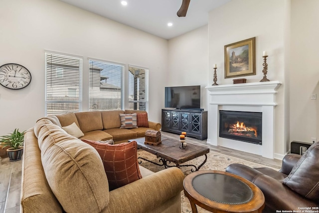 living area with a glass covered fireplace, recessed lighting, and wood finished floors