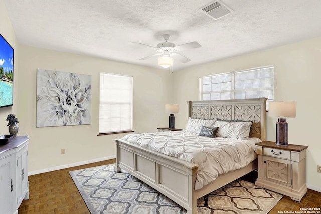 bedroom featuring visible vents, baseboards, a textured ceiling, and ceiling fan