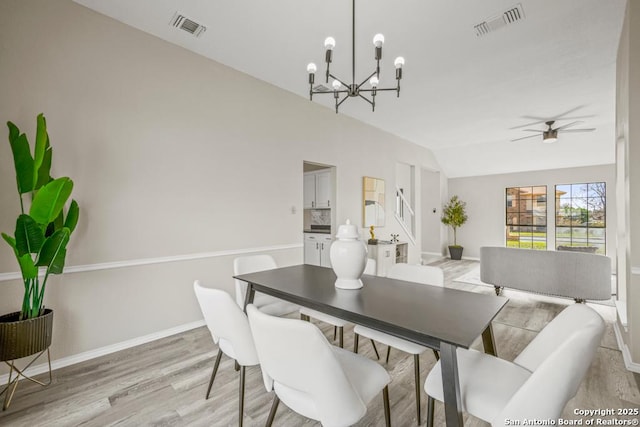 dining room with visible vents, baseboards, vaulted ceiling, and light wood finished floors