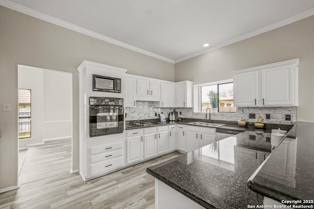 kitchen featuring a sink, black appliances, white cabinetry, tasteful backsplash, and light wood-type flooring