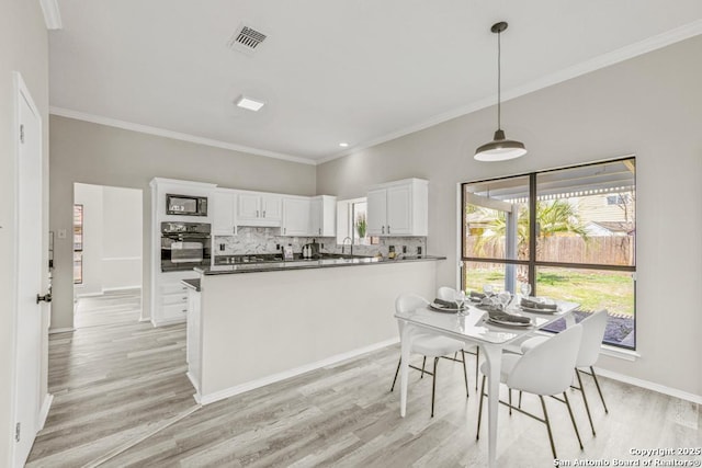 kitchen with visible vents, black appliances, tasteful backsplash, light wood-style floors, and white cabinets