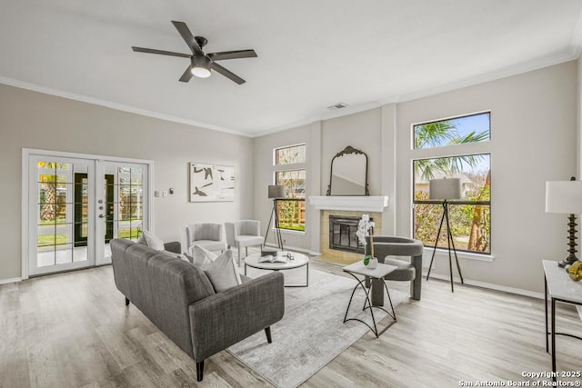 living area featuring french doors, wood finished floors, crown molding, and a tile fireplace