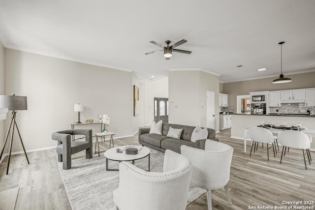 living area featuring light wood finished floors, a ceiling fan, baseboards, and ornamental molding