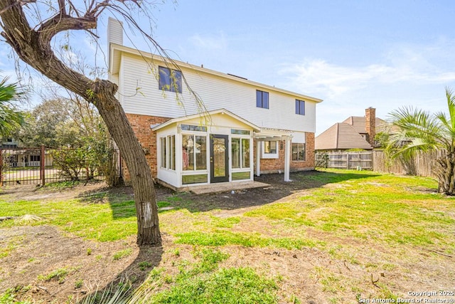 back of property featuring a yard, a fenced backyard, brick siding, and a sunroom